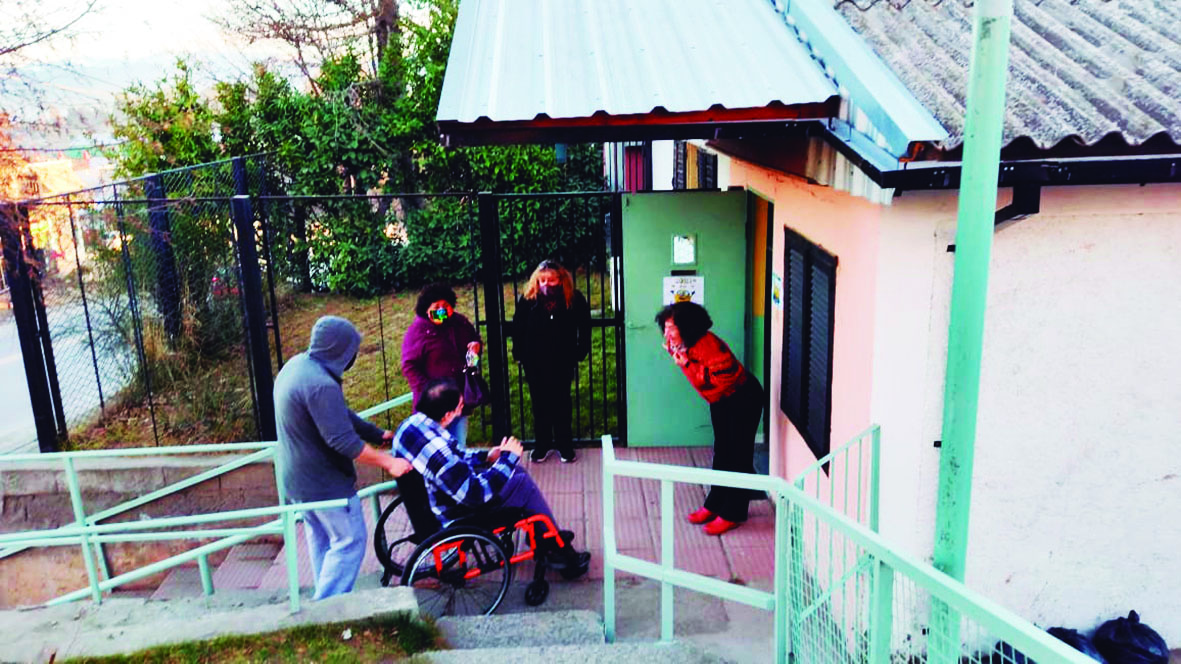 Fotografía de cuatro personas recibiendo a un hombre en silla de ruedas en la entrada de la "Asociación Esperanza".