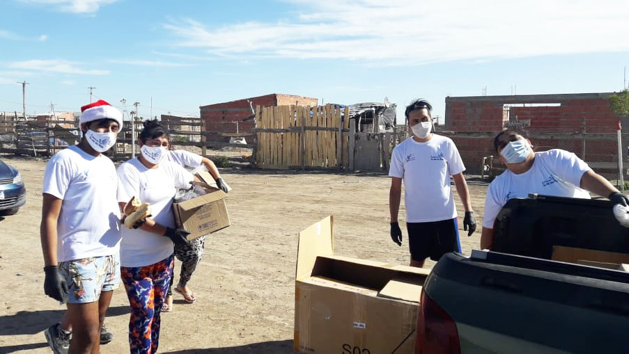 Fotografía de varias personas descargando cajas de comida, una camioneta para distribuirlas solidariamente.