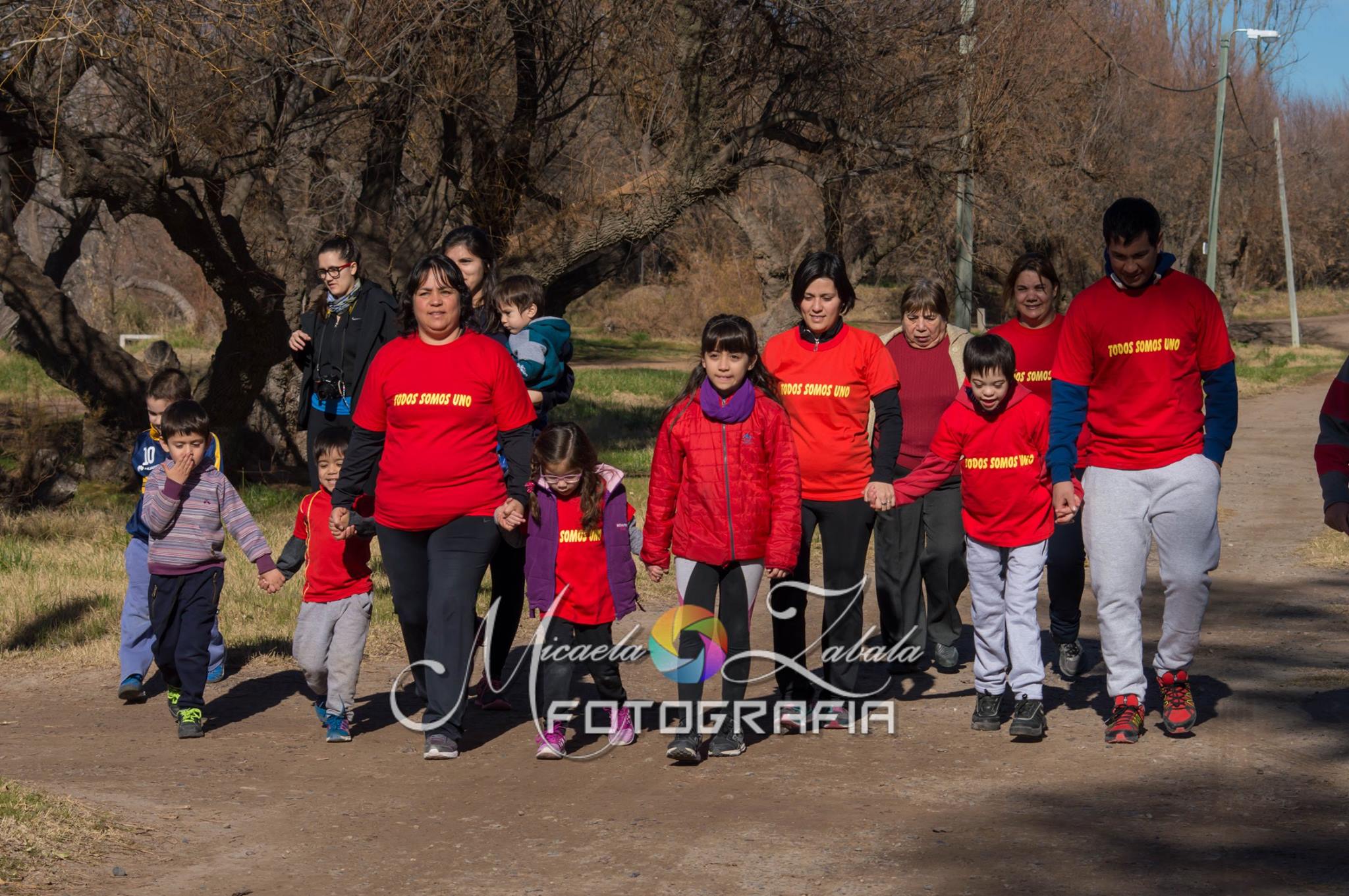 Fotografía de un grupo de adultos y niños caminando juntos en un parque.